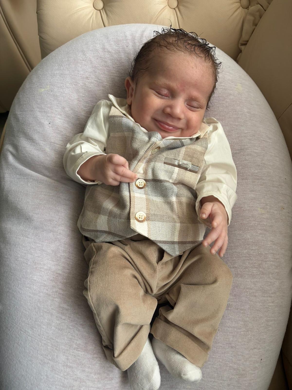 Glimlachende baby in een geruit gilet